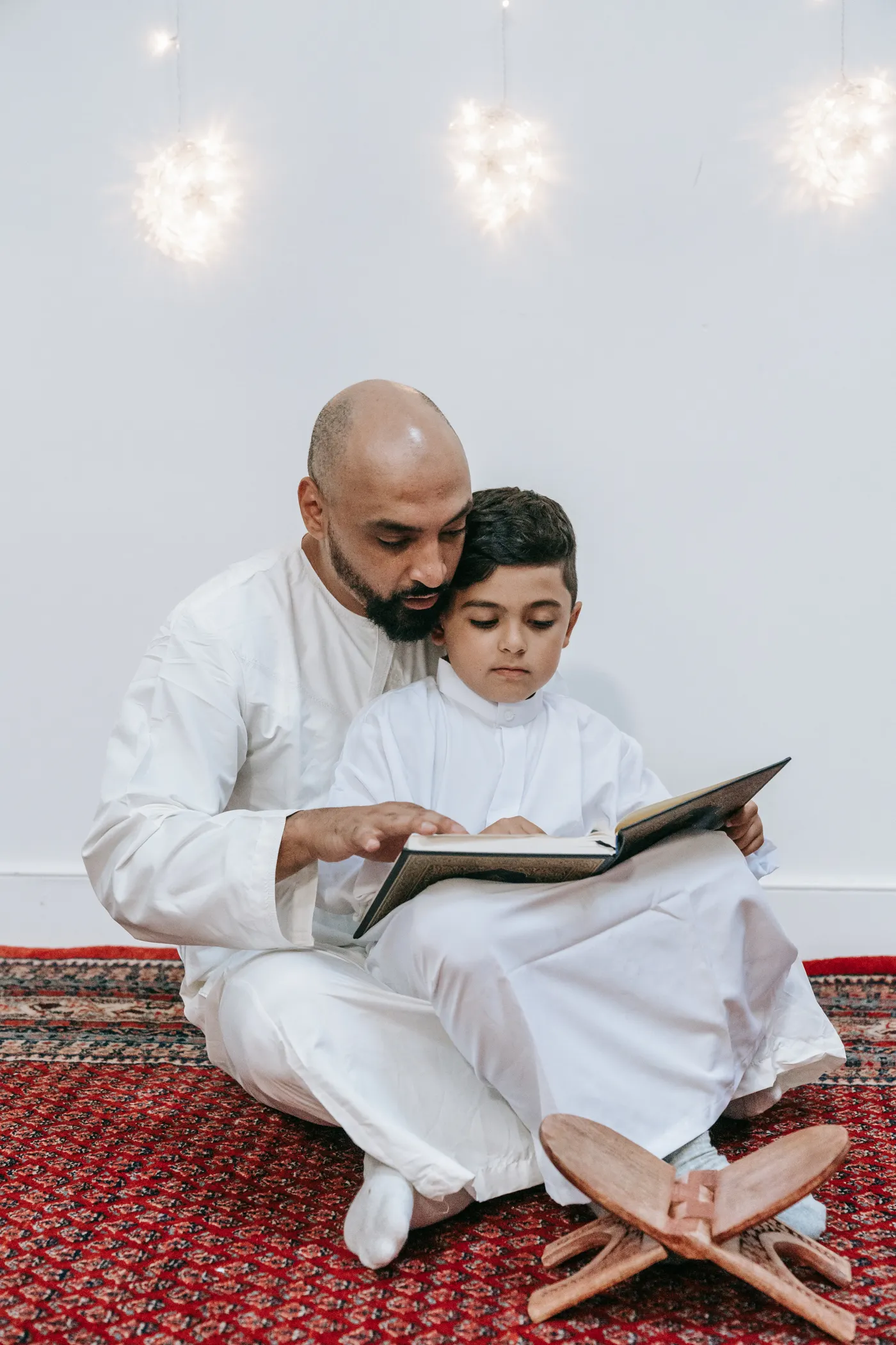 A father and his young son read the Qur’an together